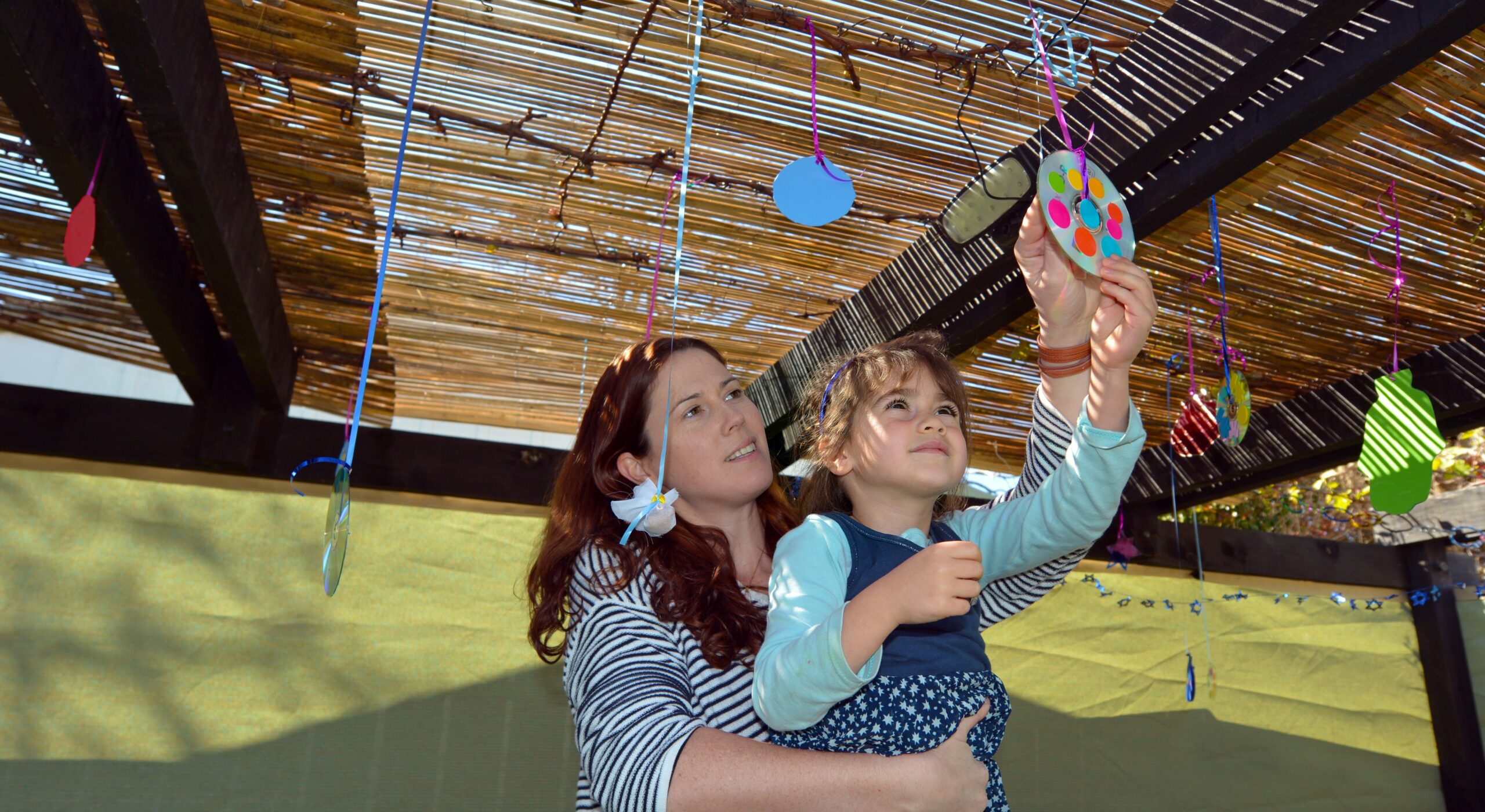 Jewish woman and child decorating their family Sukkah